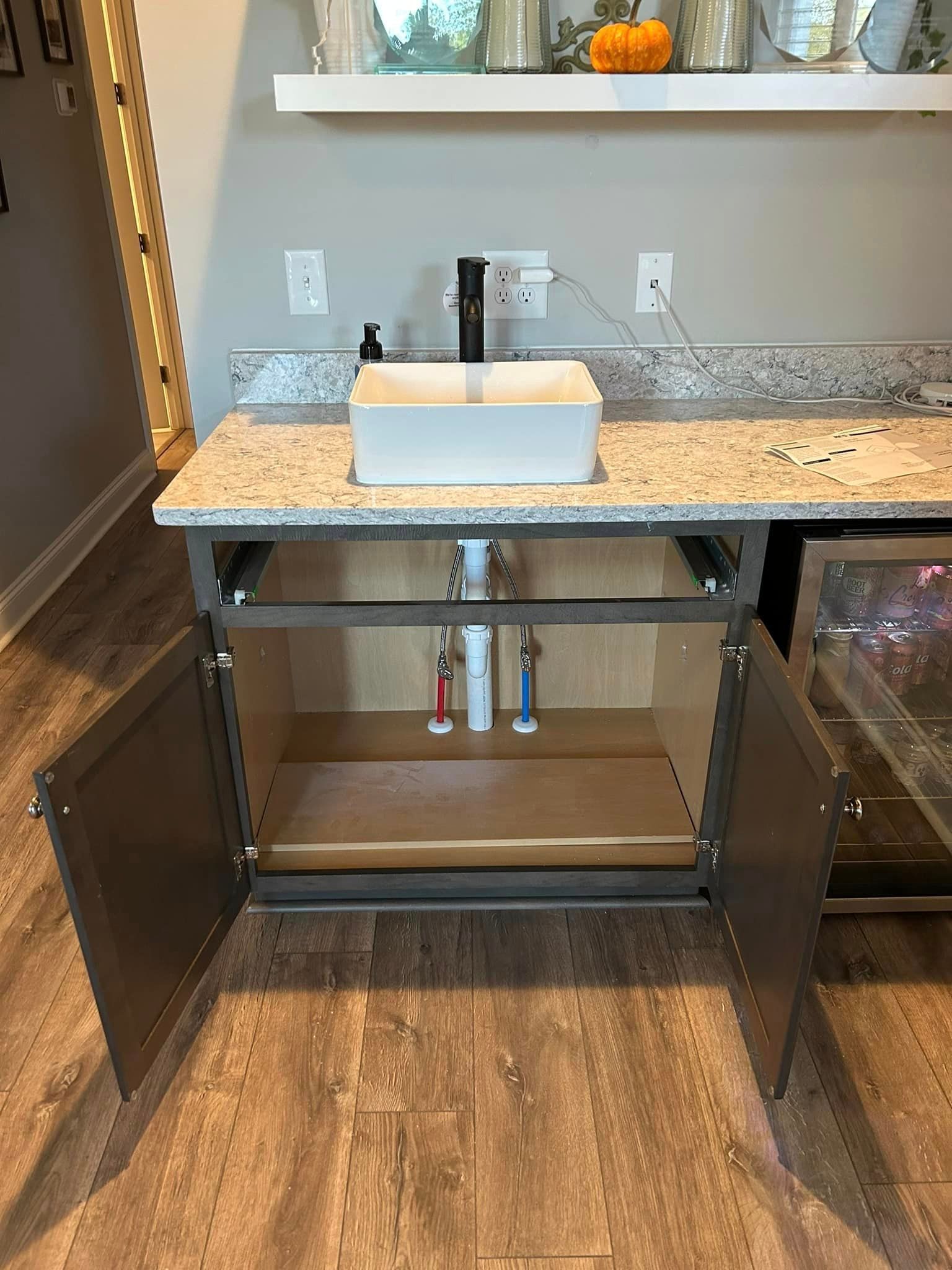 A bathroom vanity with a sink underneath it and the doors open.