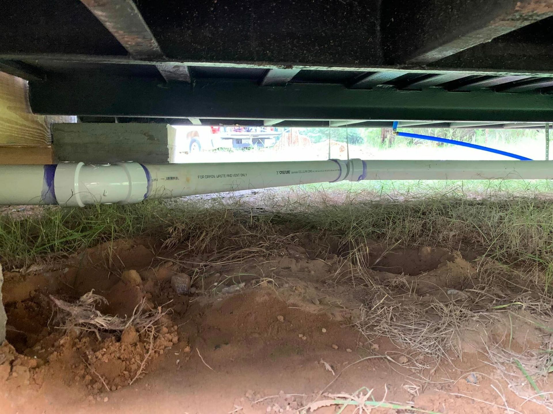 A close up of a drain pipe under a house.