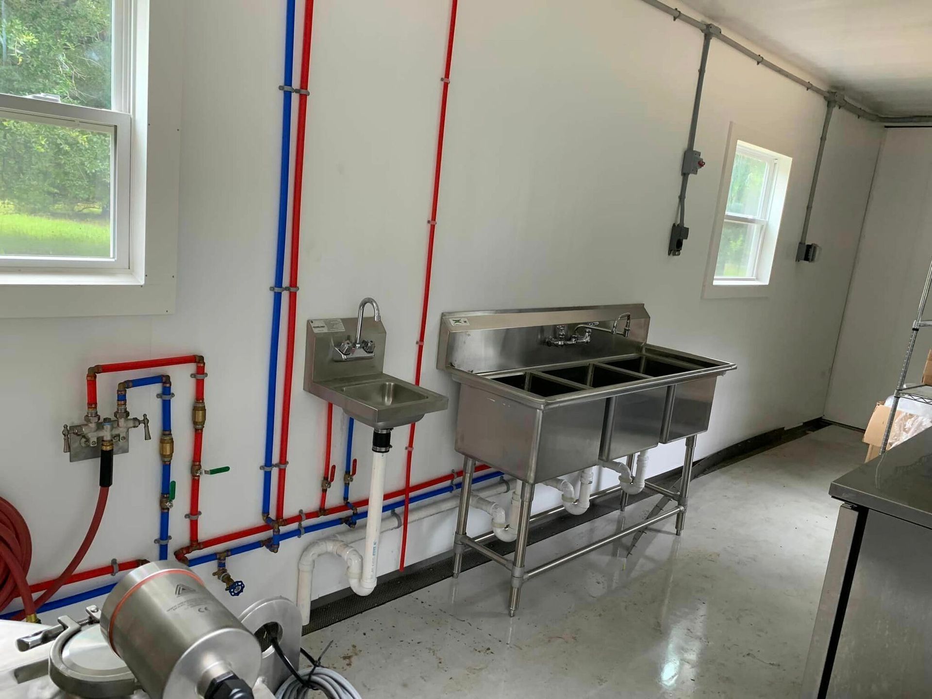 A kitchen with stainless steel sinks and a window