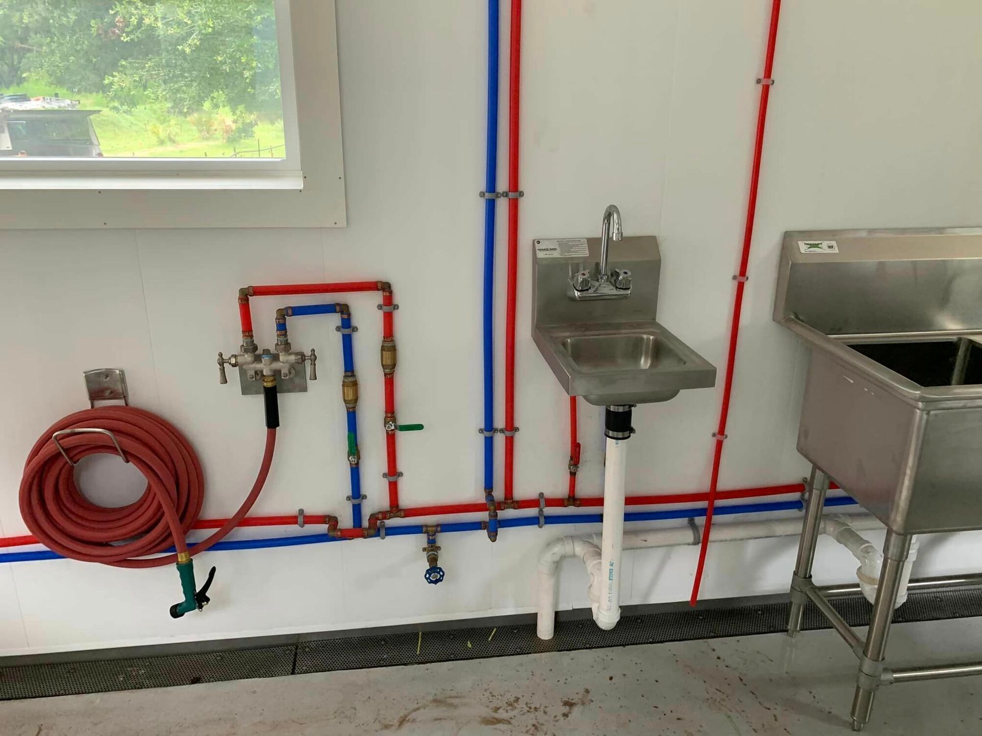 A bathroom with a sink and a hose hanging on the wall