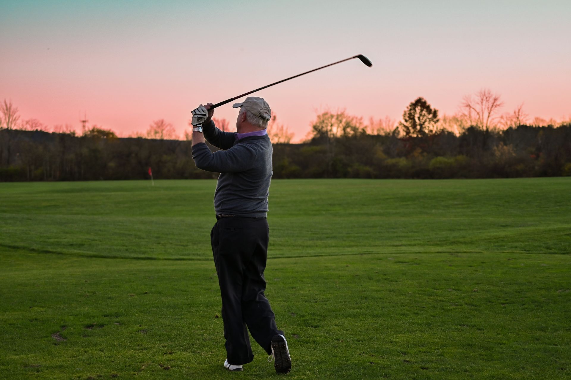 A man is swinging a golf club on a golf course.