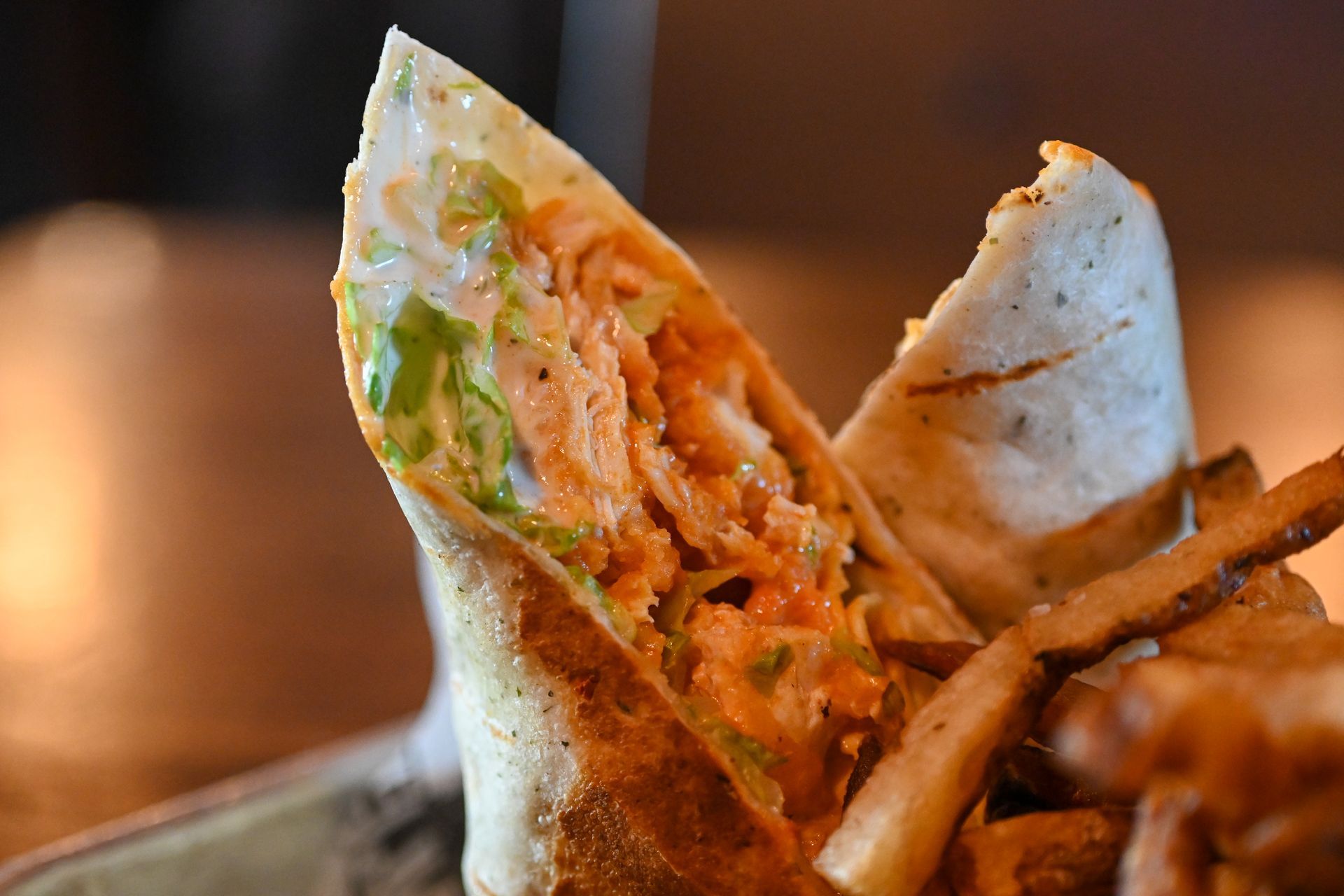 A close up of a burrito with french fries on a plate.