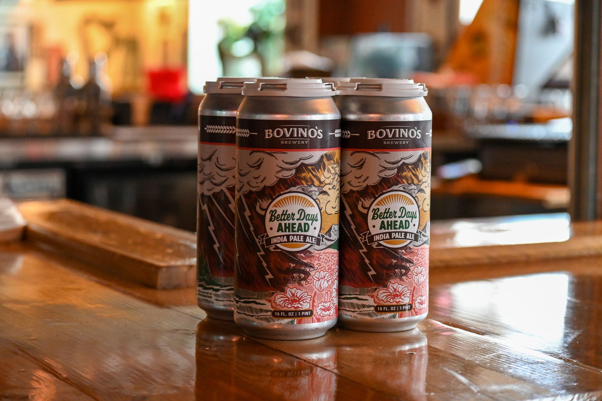 Four cans of beer are sitting on a wooden table.