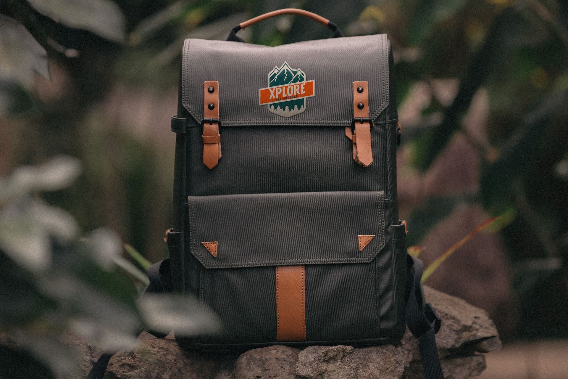 A backpack is sitting on top of a rock in the woods.