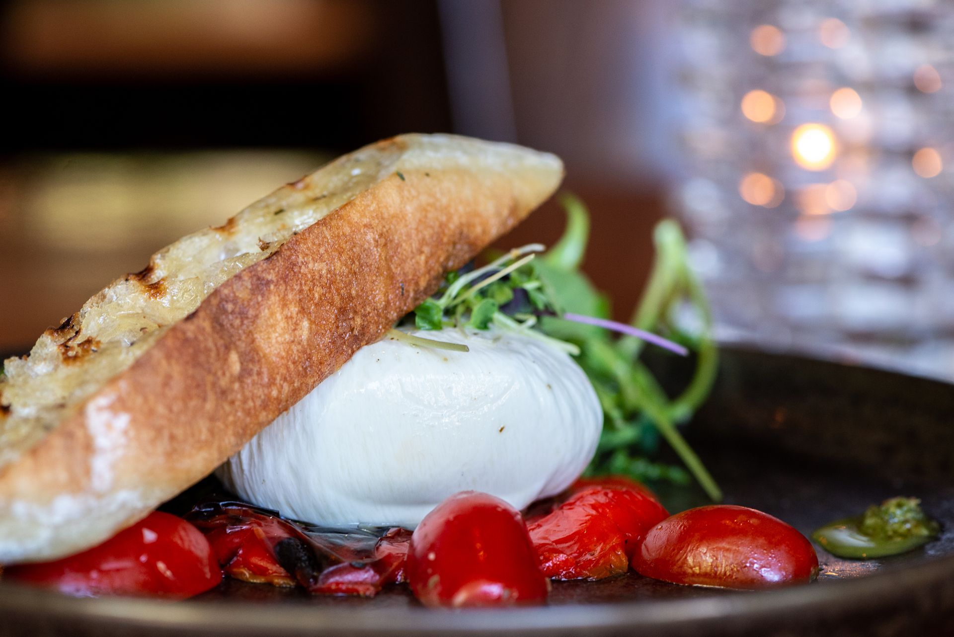 A close up of a plate of food with tomatoes and bread on a table.