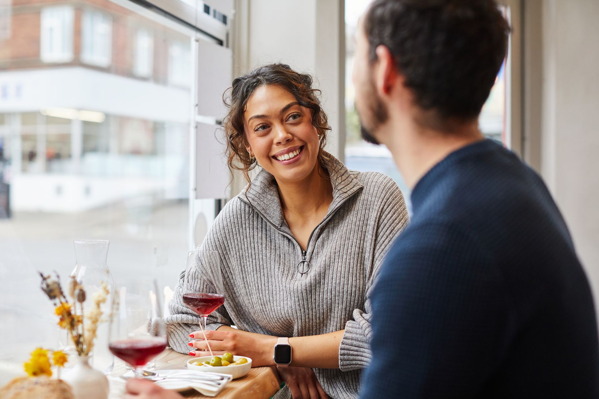 A man and a woman are walking down a sidewalk in front of a colorful wall.