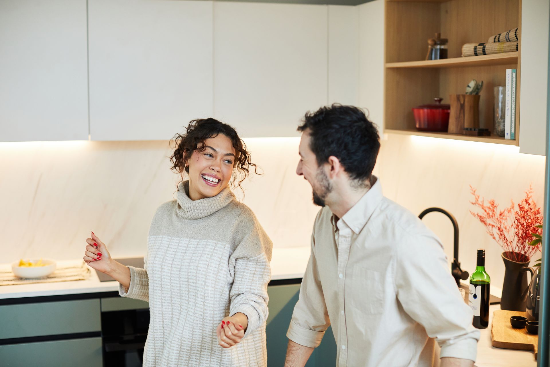 A man and a woman are dancing in a kitchen.