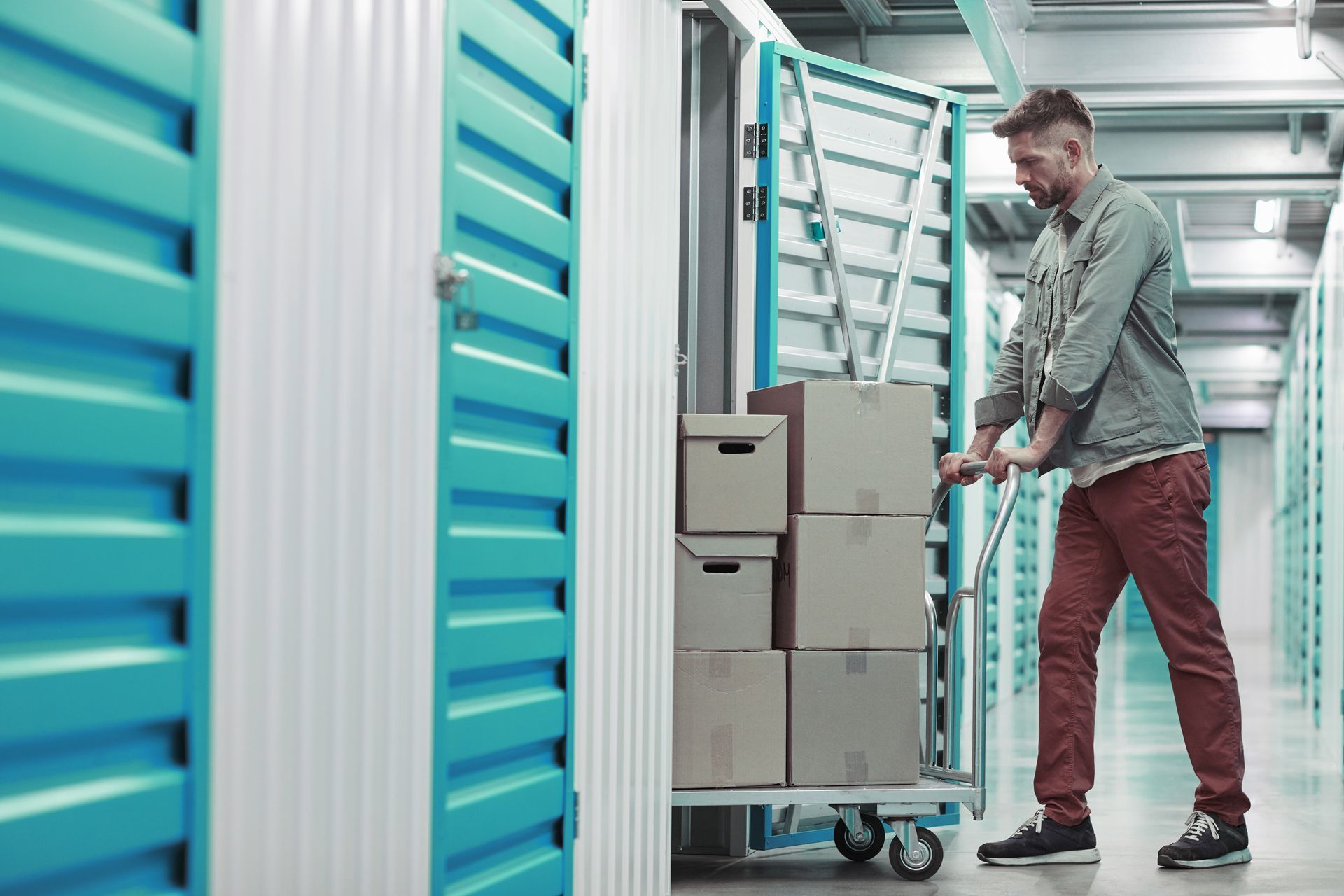 We Box Self Storage Um homem está empurrando um carrinho cheio de caixas em um depósito.