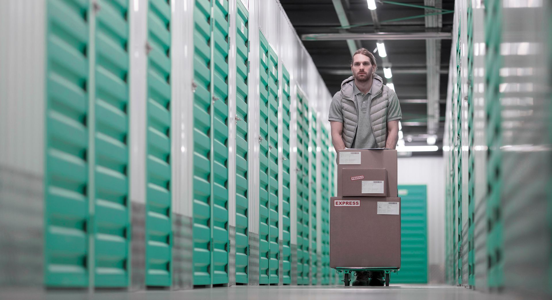 We Box Self Storage Um homem empurra um carrinho com caixas em um armazém.