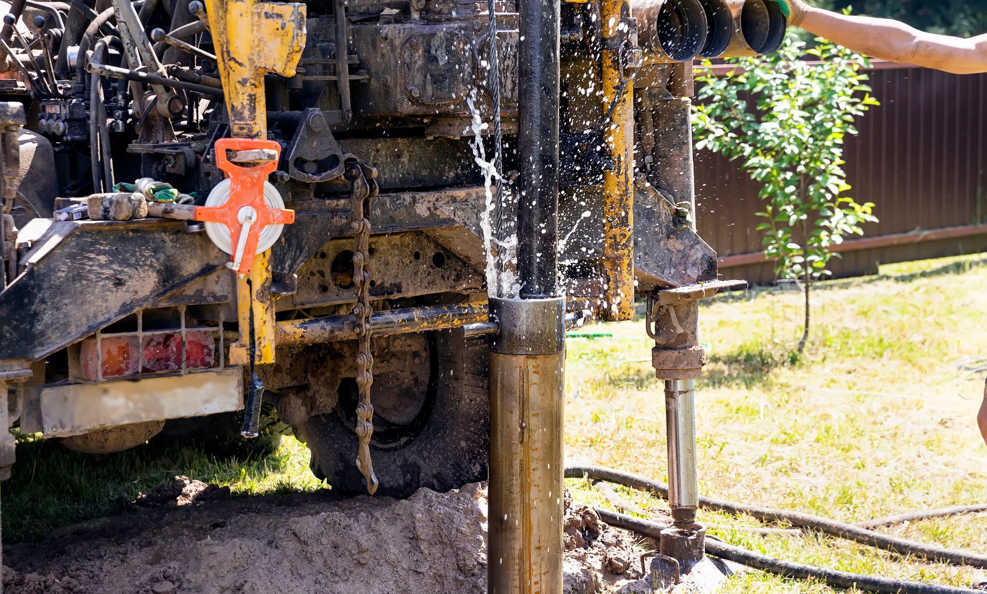 Water splashes from a drilling rig during well installation.