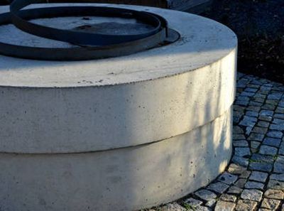 A concrete well sitting on top of a cobblestone walkway.