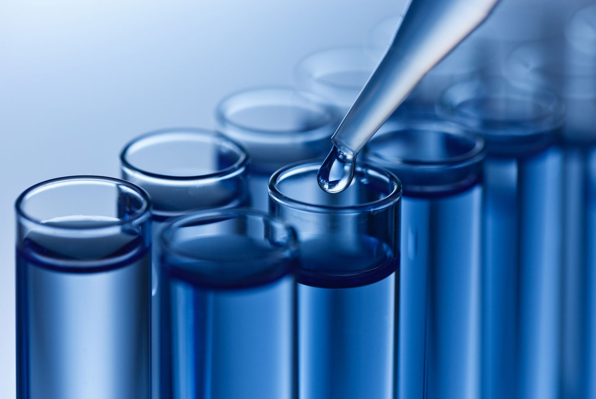 A pipette is pouring liquid into a test tube