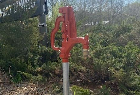 A red fire hydrant is sitting in the grass in front of a building.