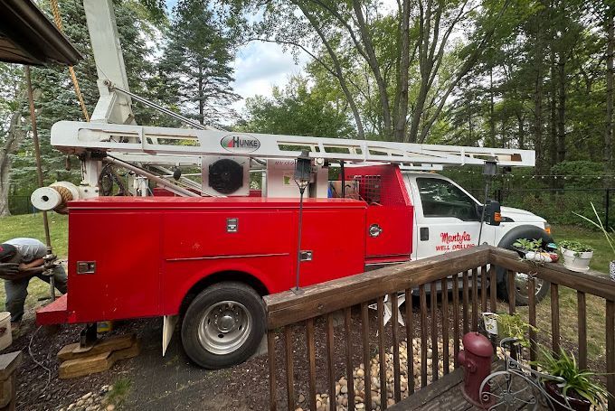 A red and white truck is parked next to a wooden deck.