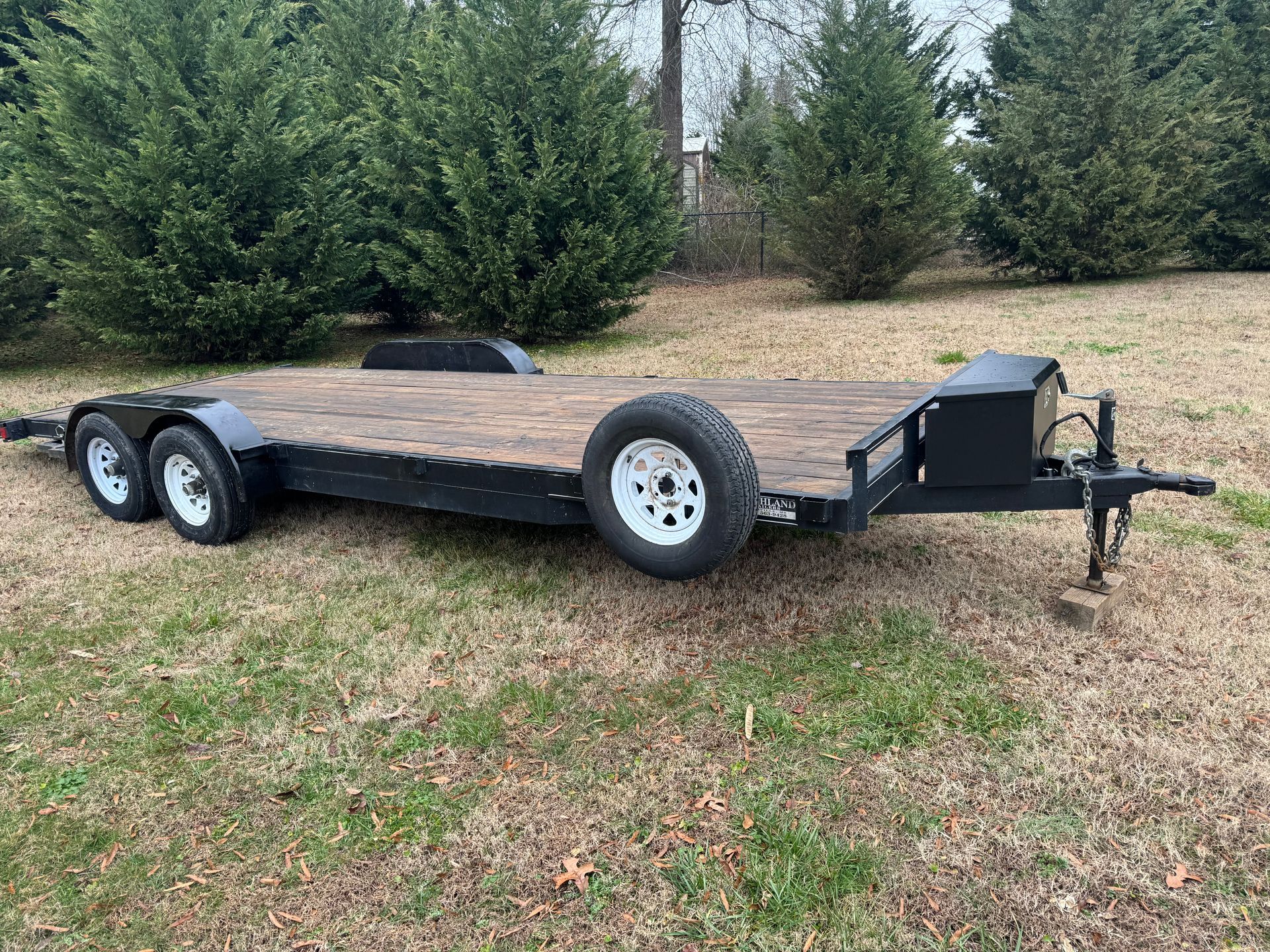 A flatbed trailer is parked in a grassy field.