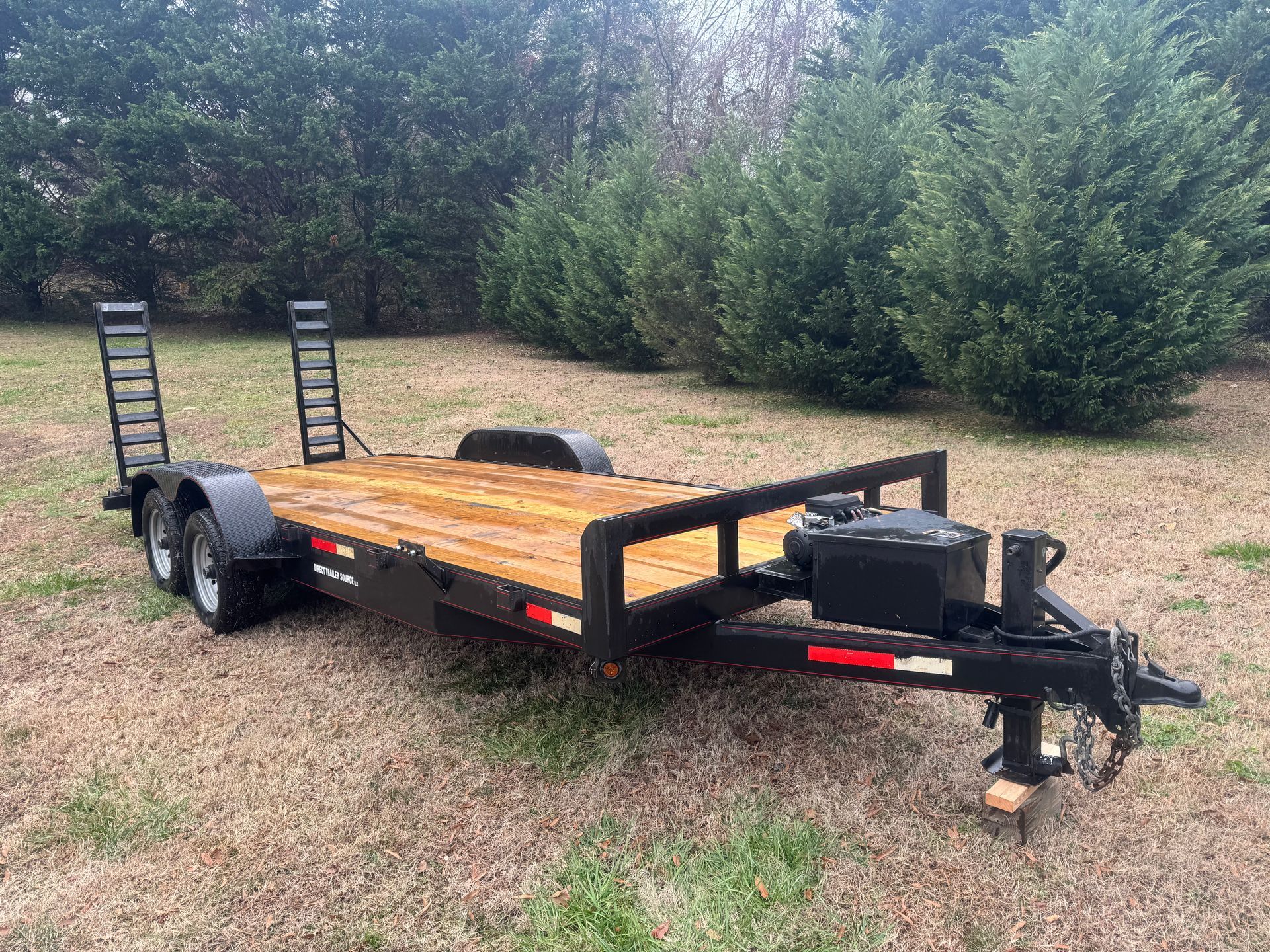 A trailer with a wooden deck is parked in a field.