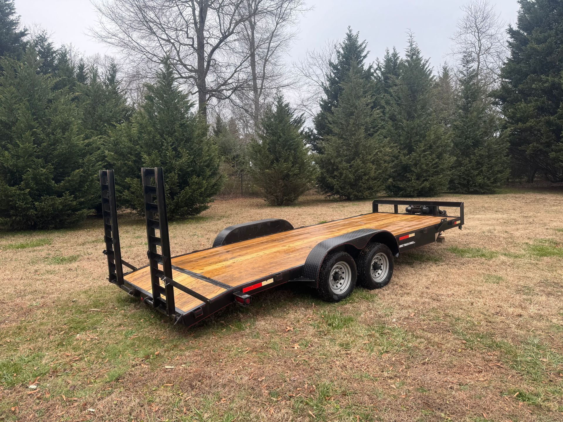 A trailer is parked in a grassy field with trees in the background.