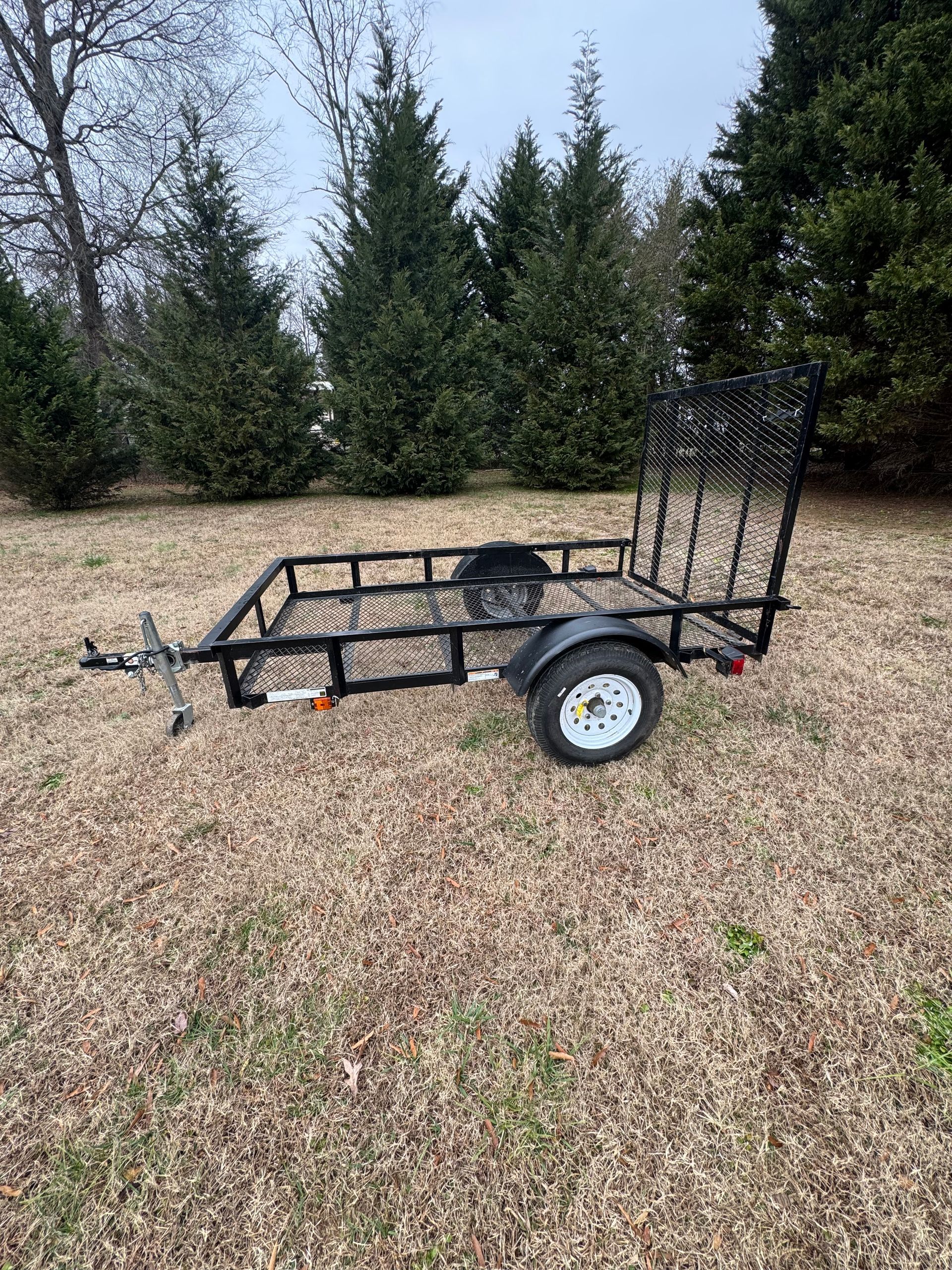 A small trailer is parked in a grassy field.