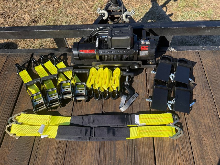 A bunch of yellow straps and a winch are sitting on a wooden table.