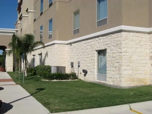 Building with stone veneer base, windows, and green lawn.