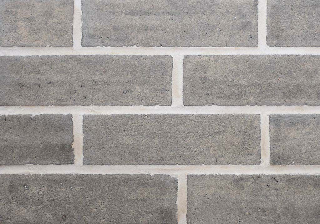 Gray brick wall with white mortar between bricks.