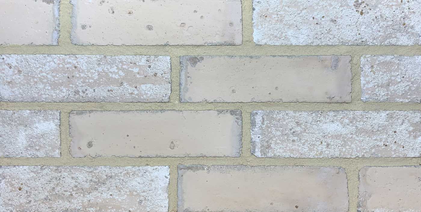 Light tan and white brick wall with gray mortar.