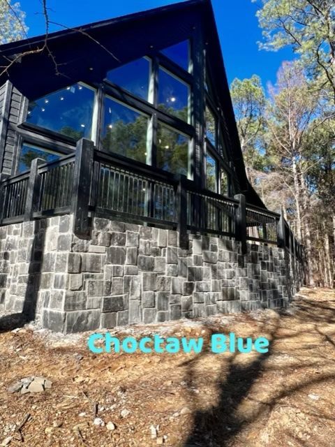 Black cabin with a stone base and large windows, labeled 