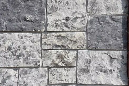 Gray and white stone wall with a textured, rectangular pattern.