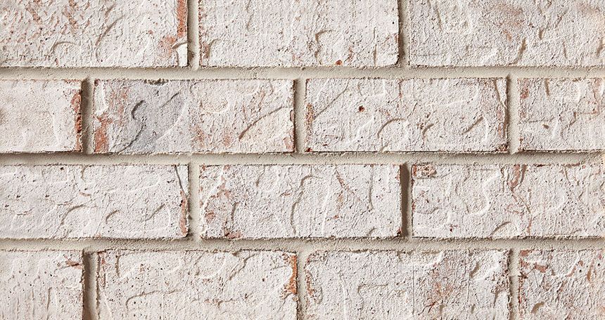 White painted brick wall with textured surface and gray mortar.