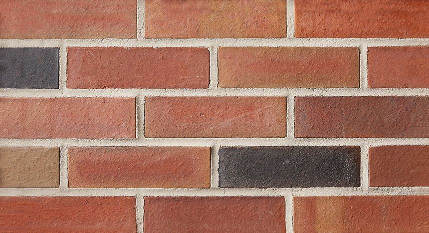 Red and brown brick wall with light gray mortar, varied brick colors.