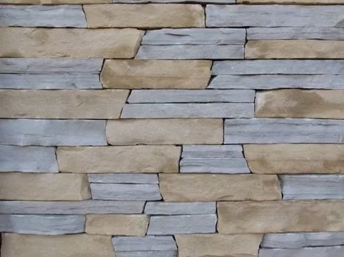 Stone wall with alternating light brown and gray rectangular blocks.