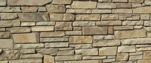 Close-up of a stone wall with various rectangular and irregular shapes in shades of brown and tan.
