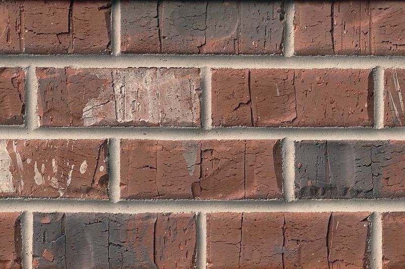 Close-up of a brick wall with red-brown bricks and light gray mortar.