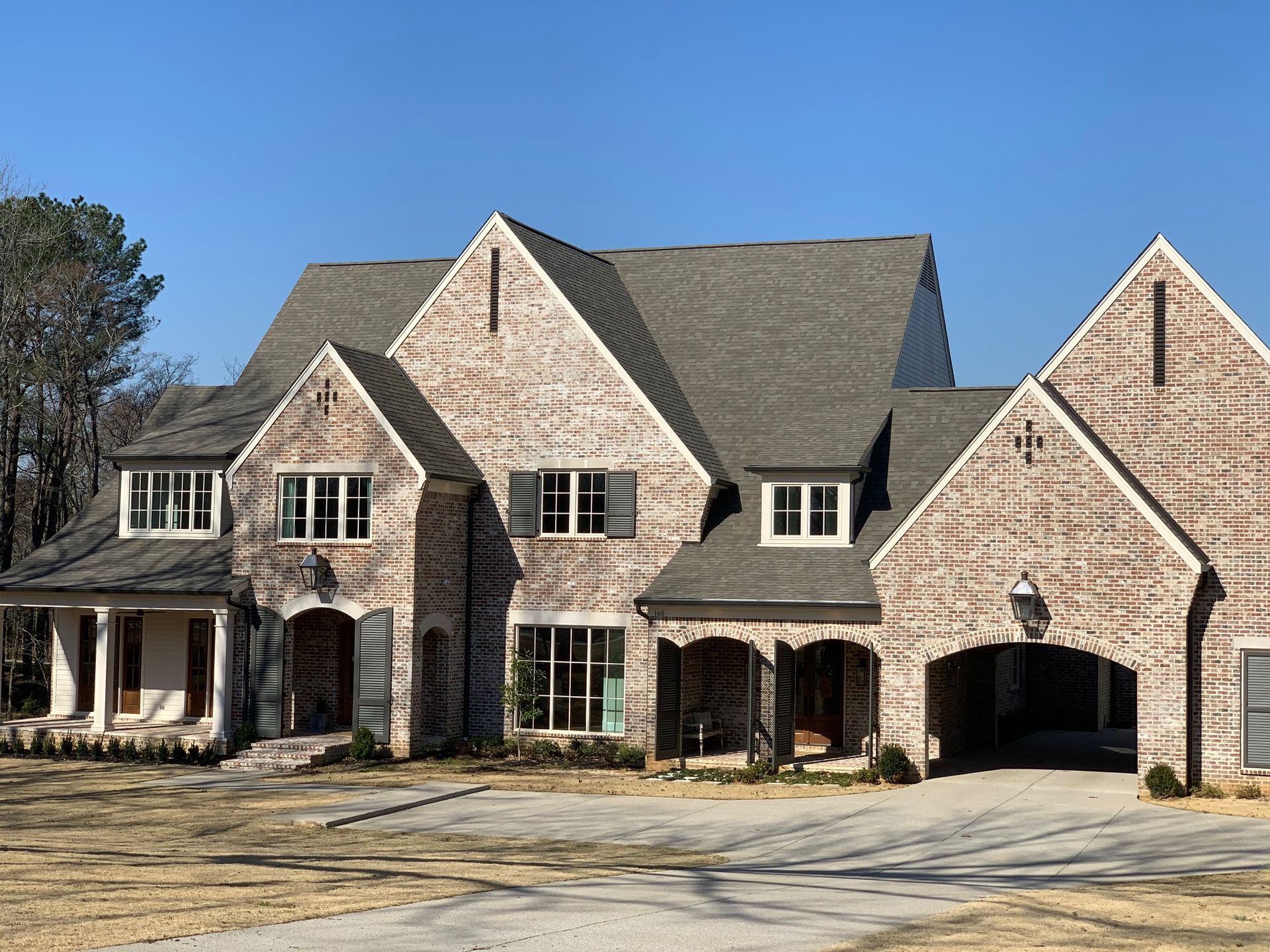 Brick home with multiple gabled roof sections, small windows, and a covered porch.
