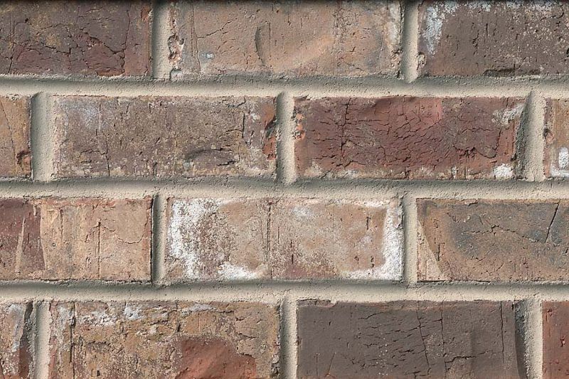 Close-up of a brick wall with varying shades of brown and reddish-brown bricks, separated by light gray mortar.