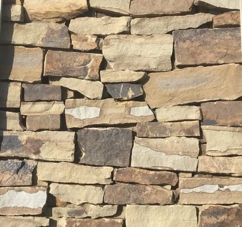 Close-up of a wall made of rectangular, light brown and tan natural stones.