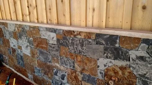 Stone veneer base on a wall with wooden planks above; gray, brown, and tan tones.