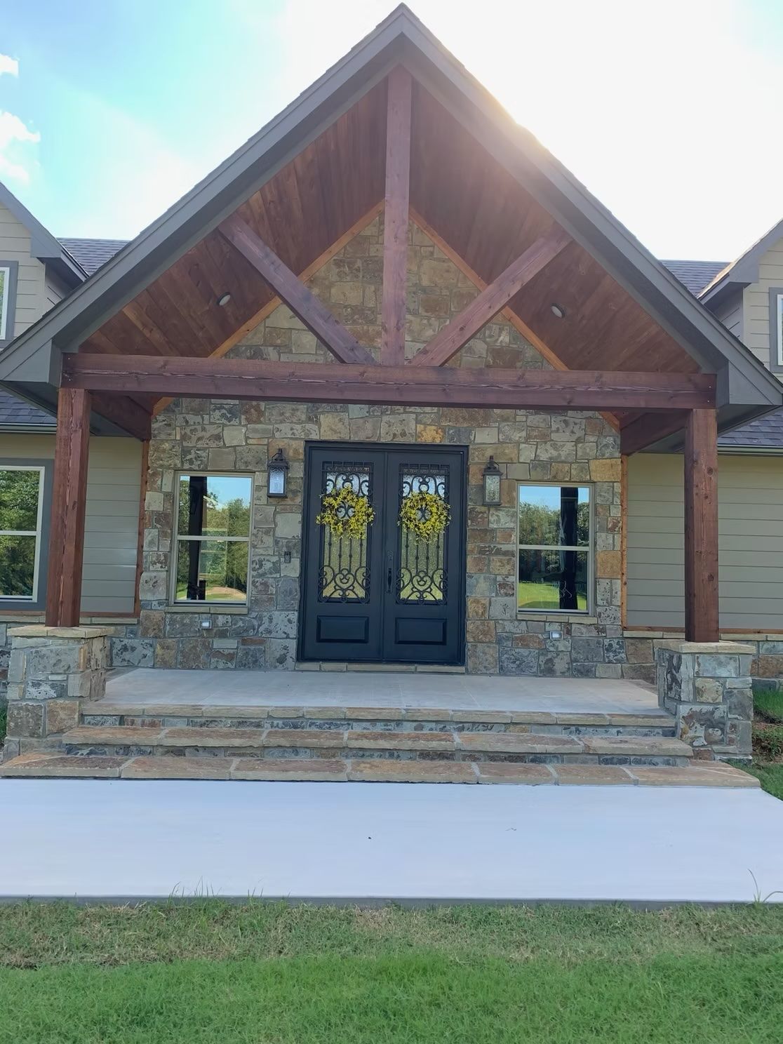 Stone and wood facade with double doors, under a gabled roof. Exterior of a house with steps.