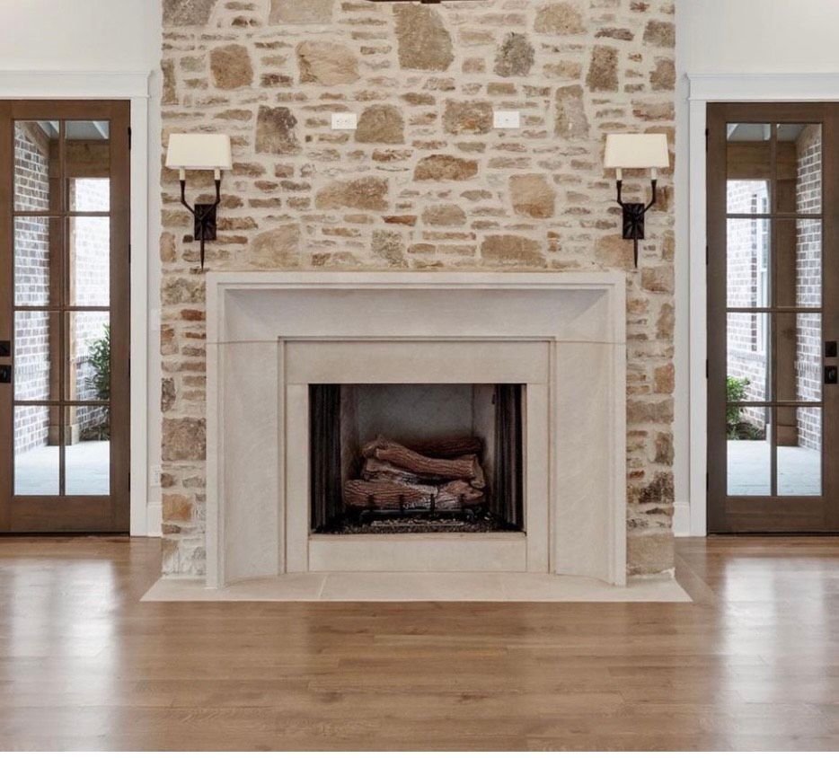 Stone fireplace with sconces, flanked by two glass-paneled doors on wood flooring.