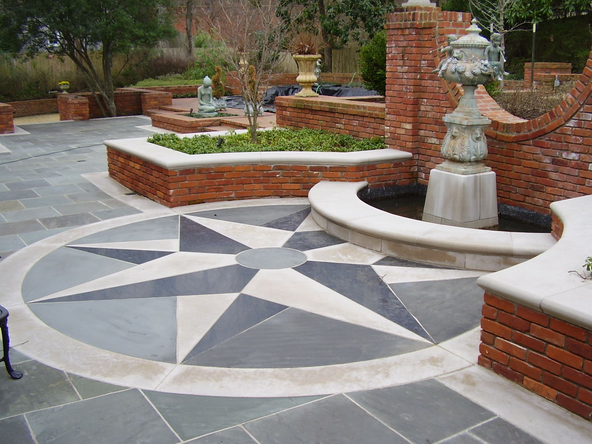 Outdoor patio with compass rose design, brick walls, and fountain.