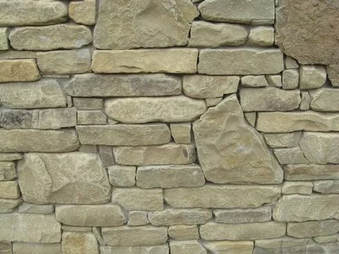 Stone wall constructed with light-colored, irregularly shaped stones of varying sizes and tones.