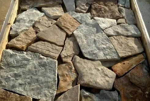 Box of irregular-shaped natural stones in shades of gray, brown, and tan.