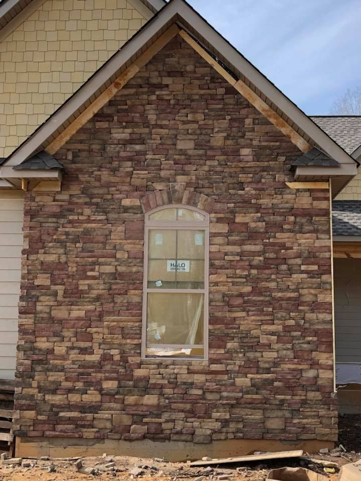 Brick wall with arched window under gable roof; construction site.