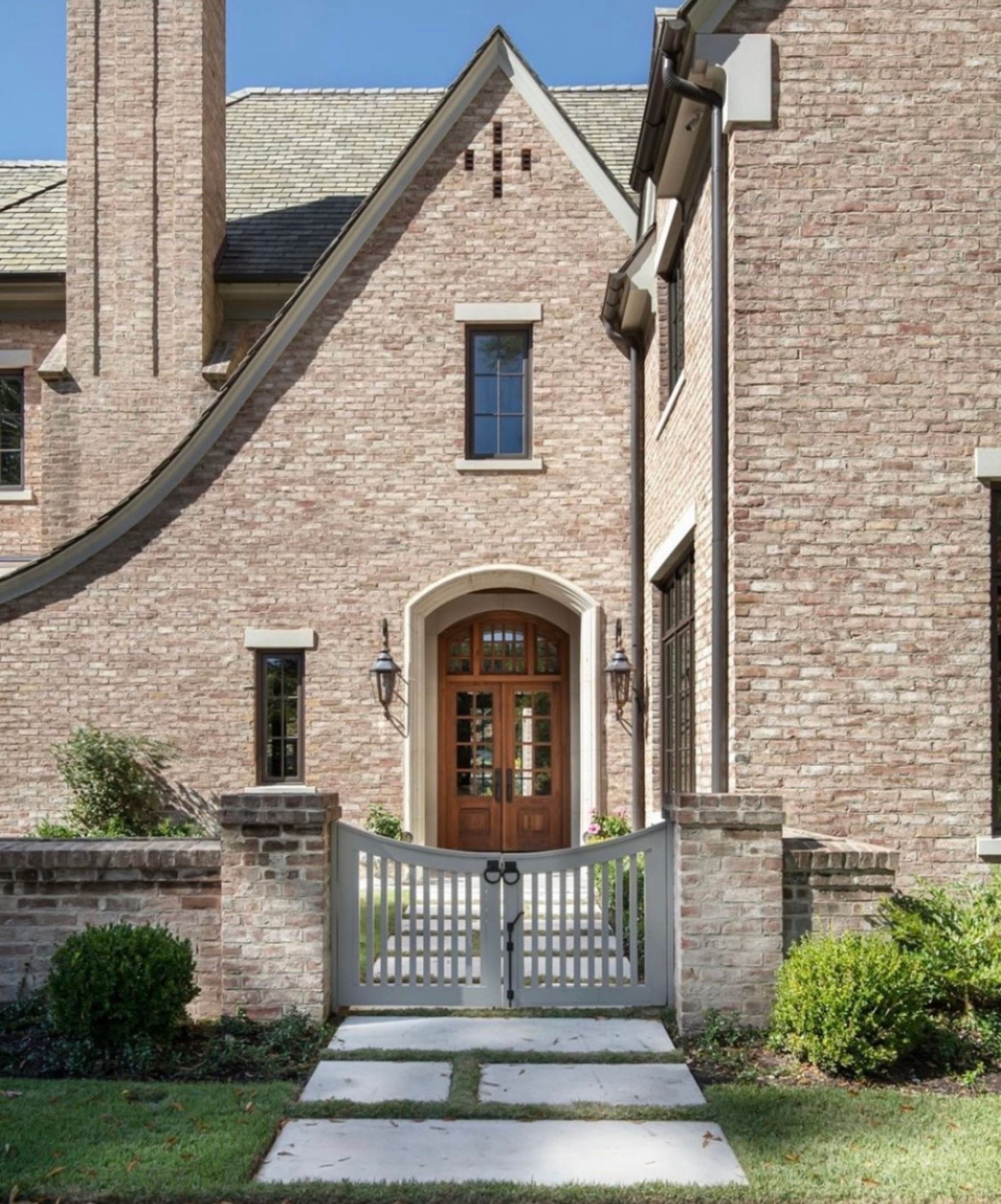 Brick home exterior with wooden door, gate, and pathway.