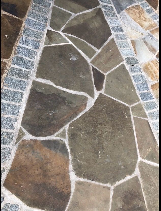 Stone tile flooring in shades of brown, gray, and tan with white grout.