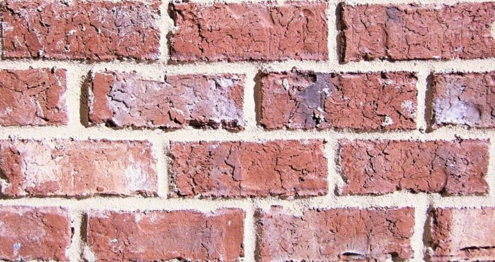 Red brick wall with weathered texture and light mortar.