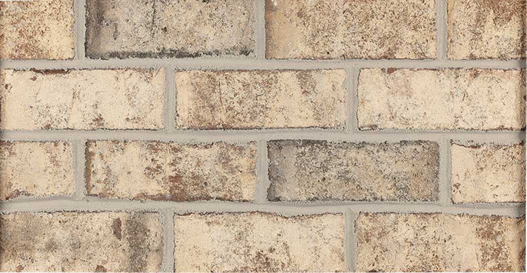 Tan and brown brick wall with gray mortar.