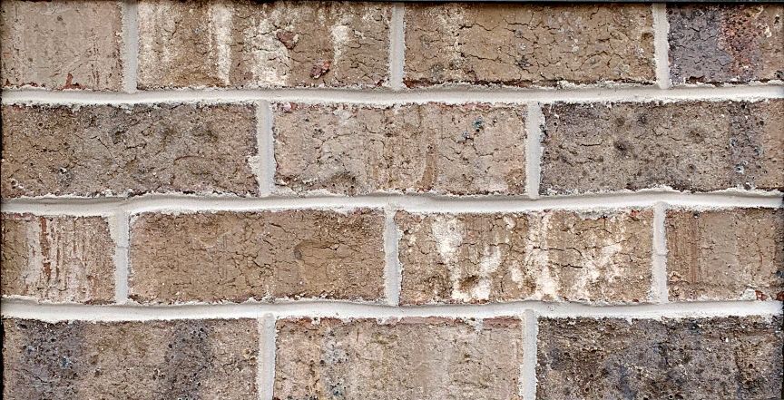 Brick wall with varying shades of brown and tan bricks and white mortar.