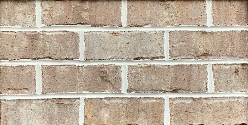 Close-up of a brick wall with light brown bricks and white mortar.