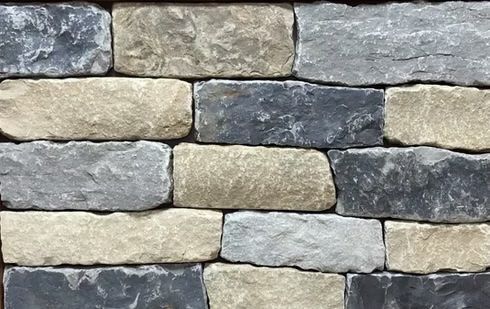 Close-up of a stone wall. The stones vary in color from gray to tan to dark blue-gray.